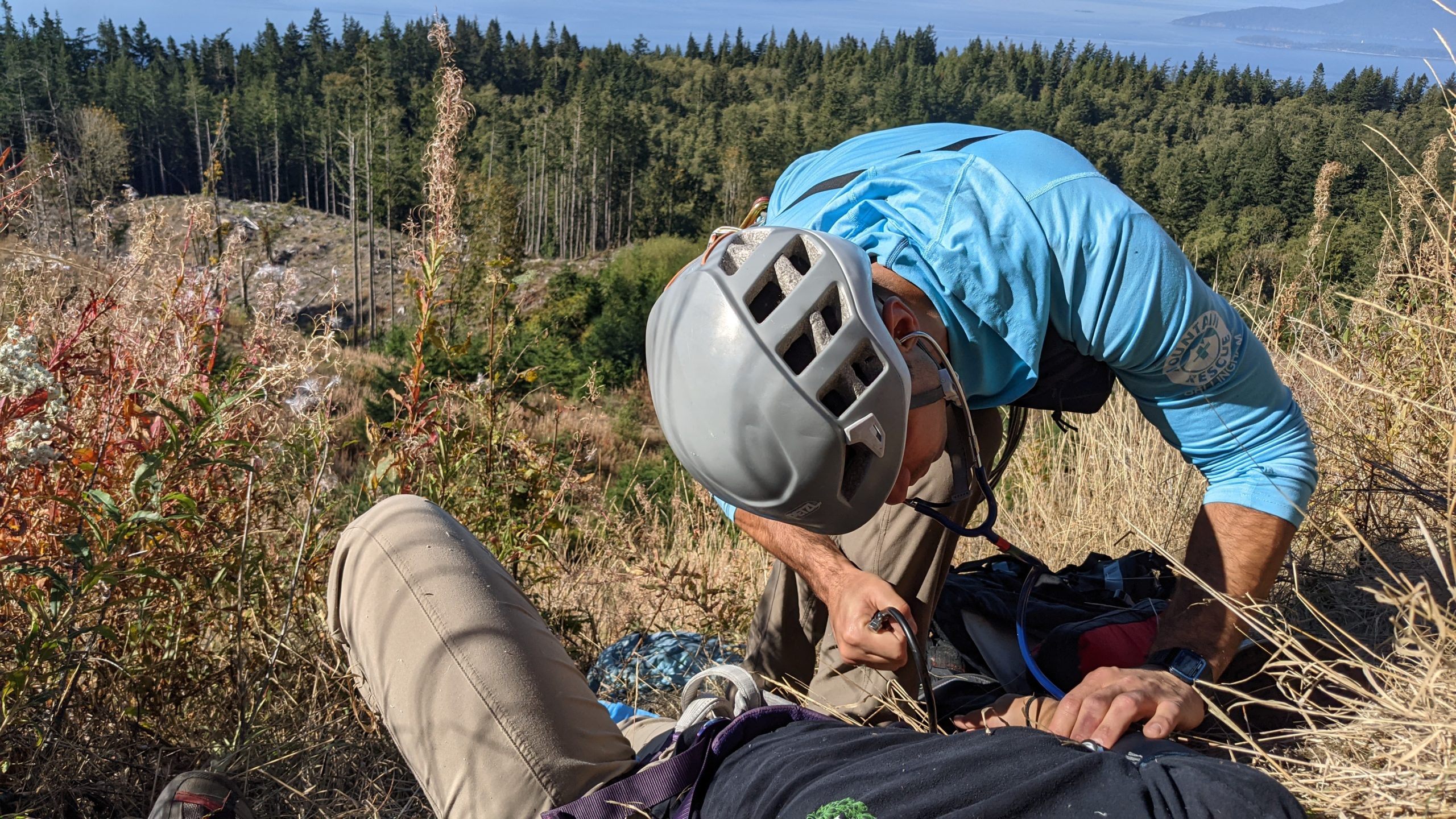 A rescuer measures blood pressure in a picturesque setting overlooking the Salish Sea